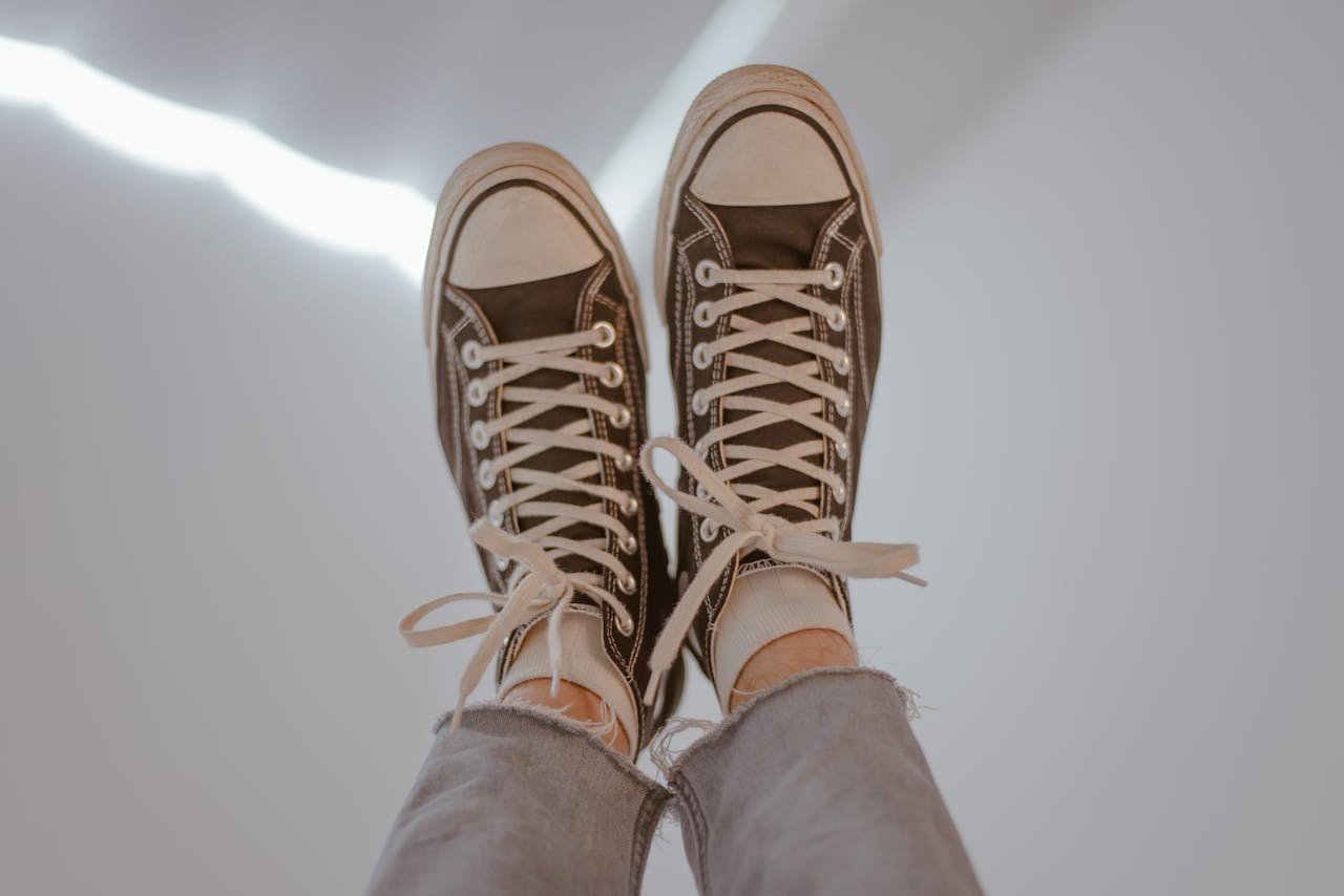 Pair of casual sneakers worn with jeans, suggesting a laid-back vibe.