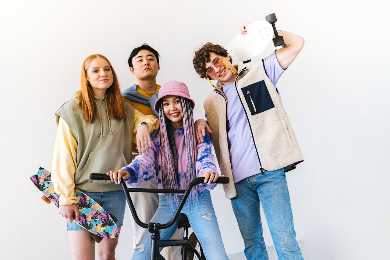 gallery-04 Four stylish friends posing with skateboards and a bicycle in a studio setting.